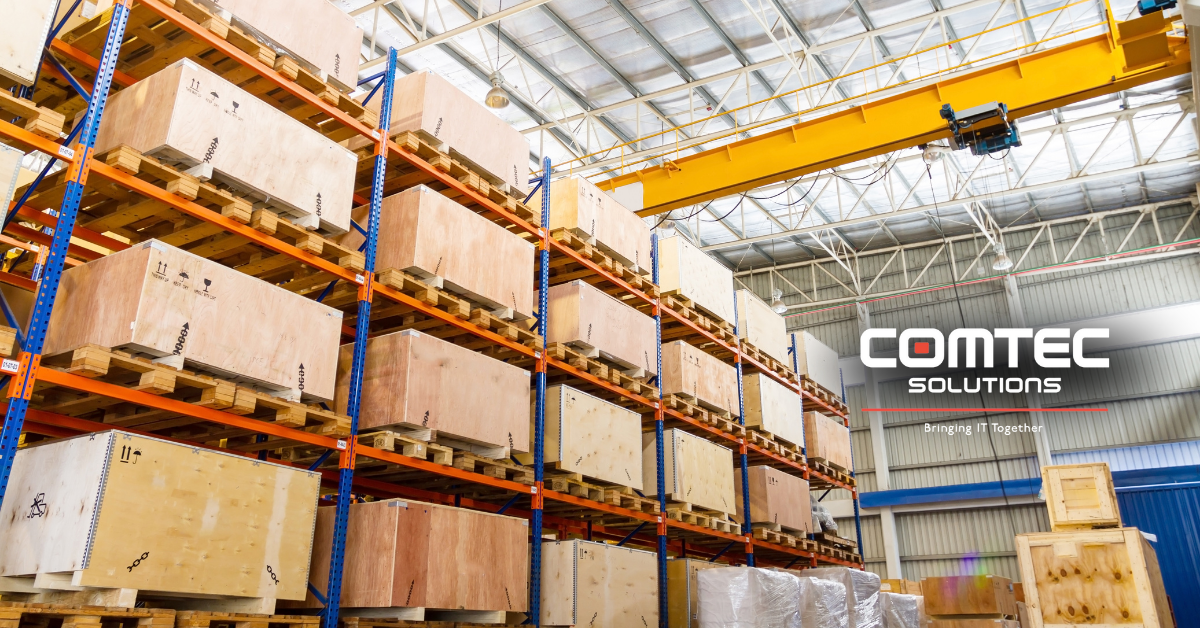 Three workers in vests and headsets stand in a warehouse. One holds a clipboard. 'COMTEC SOLUTIONS – Bringing IT Together' appears above.